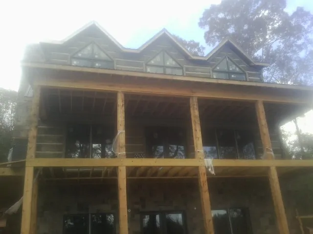 Dormers and porch framing on a large log home under construction — Roof Coating work by our crew in Stanleytown