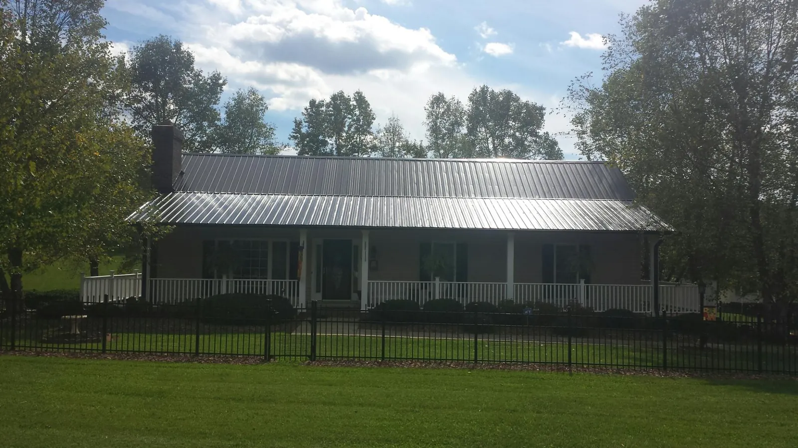 Gray metal roof on a brick ranch with a full width front porch — Gutter Guard Installation work by our crew in Stanleytown