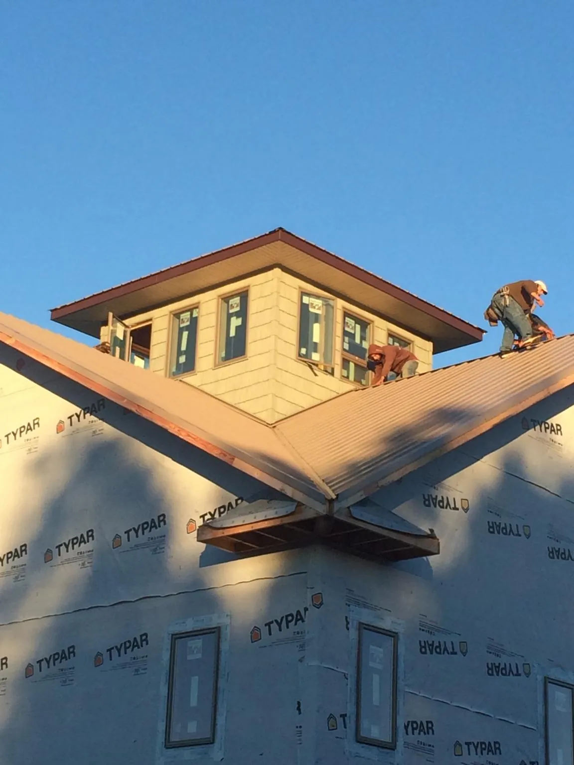 Roofers working around a rooftop cupola on a new metal roof at sunset — Roof Waterproofing in Stanleytown by Roofing Brothers